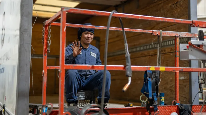 Technician on a lift working on a van body