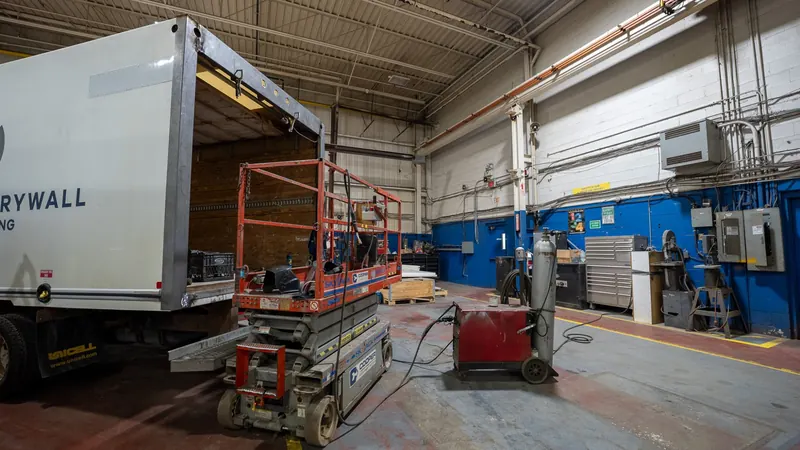 Dry freight body on a lift beside a scissor lift