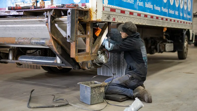Technician working under the rear of a truck body